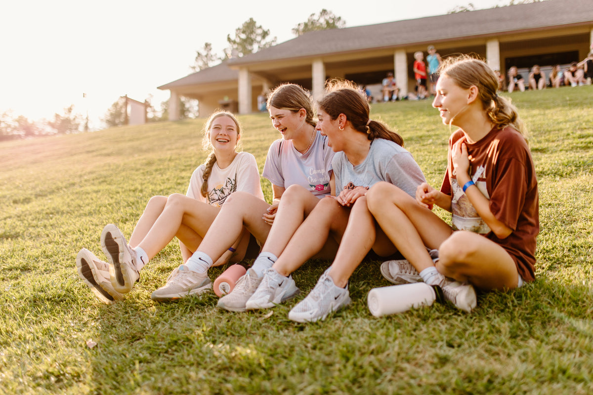Four campers laughing together on the grass at Camp Cho-Yeh