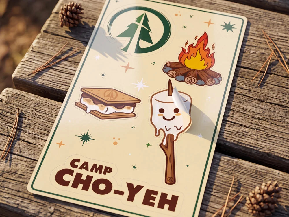 The Cho-Yeh s’more sticker sheet on a weathered picnic table, one marshmallow sticker peeling up